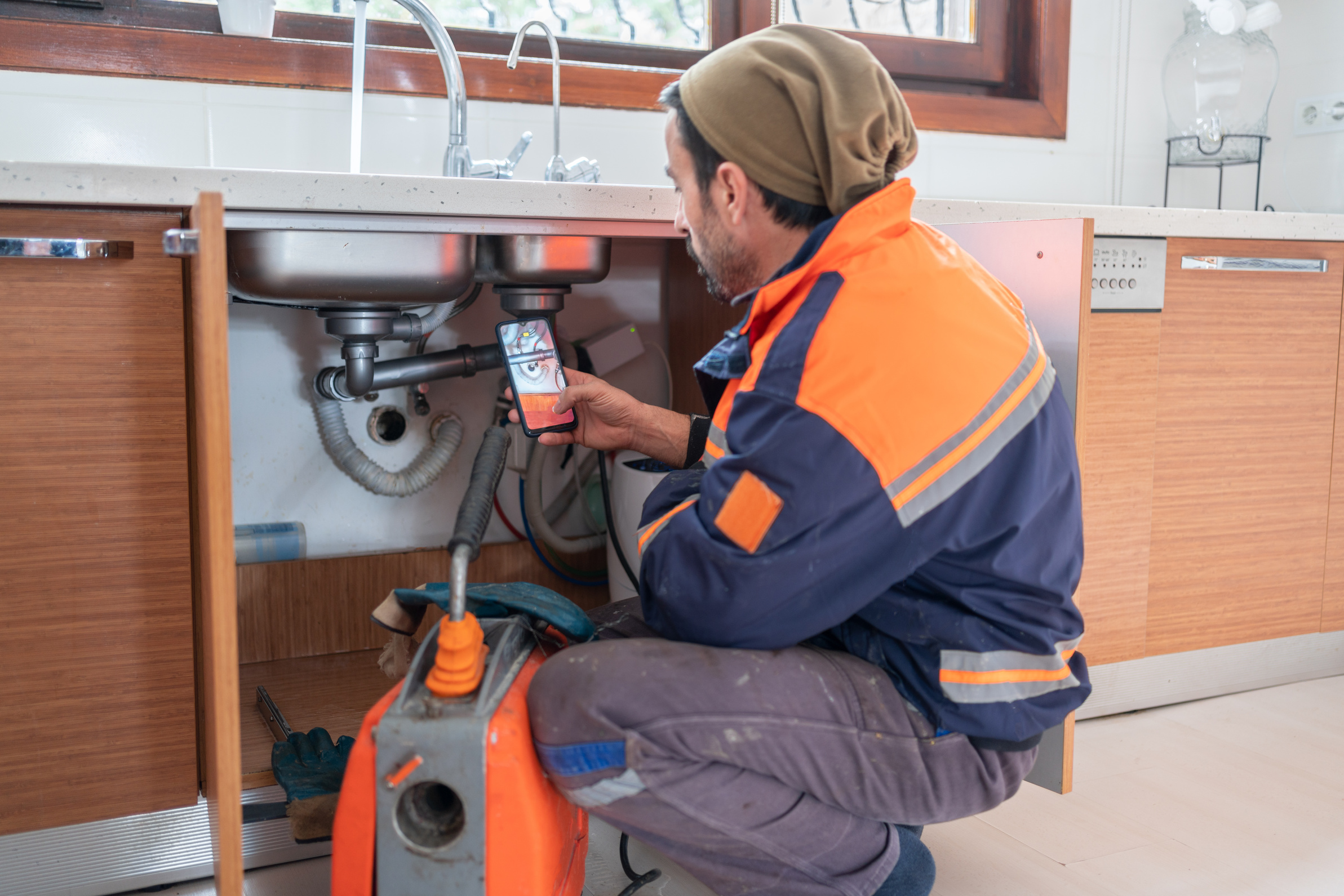 Plumber Unclogging A Kitchen Sink Drain